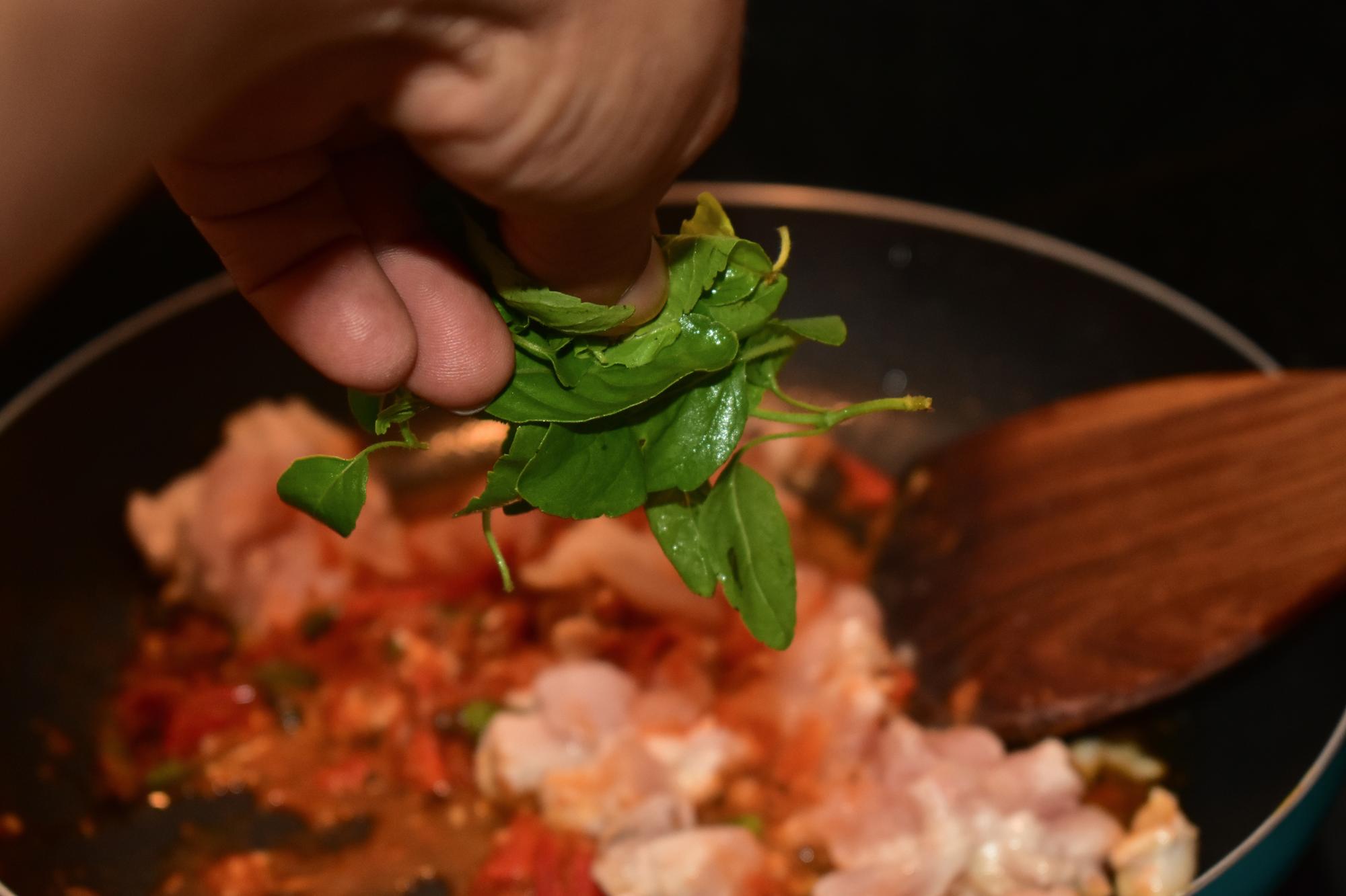 Close-up of hands plating a dish with herbs