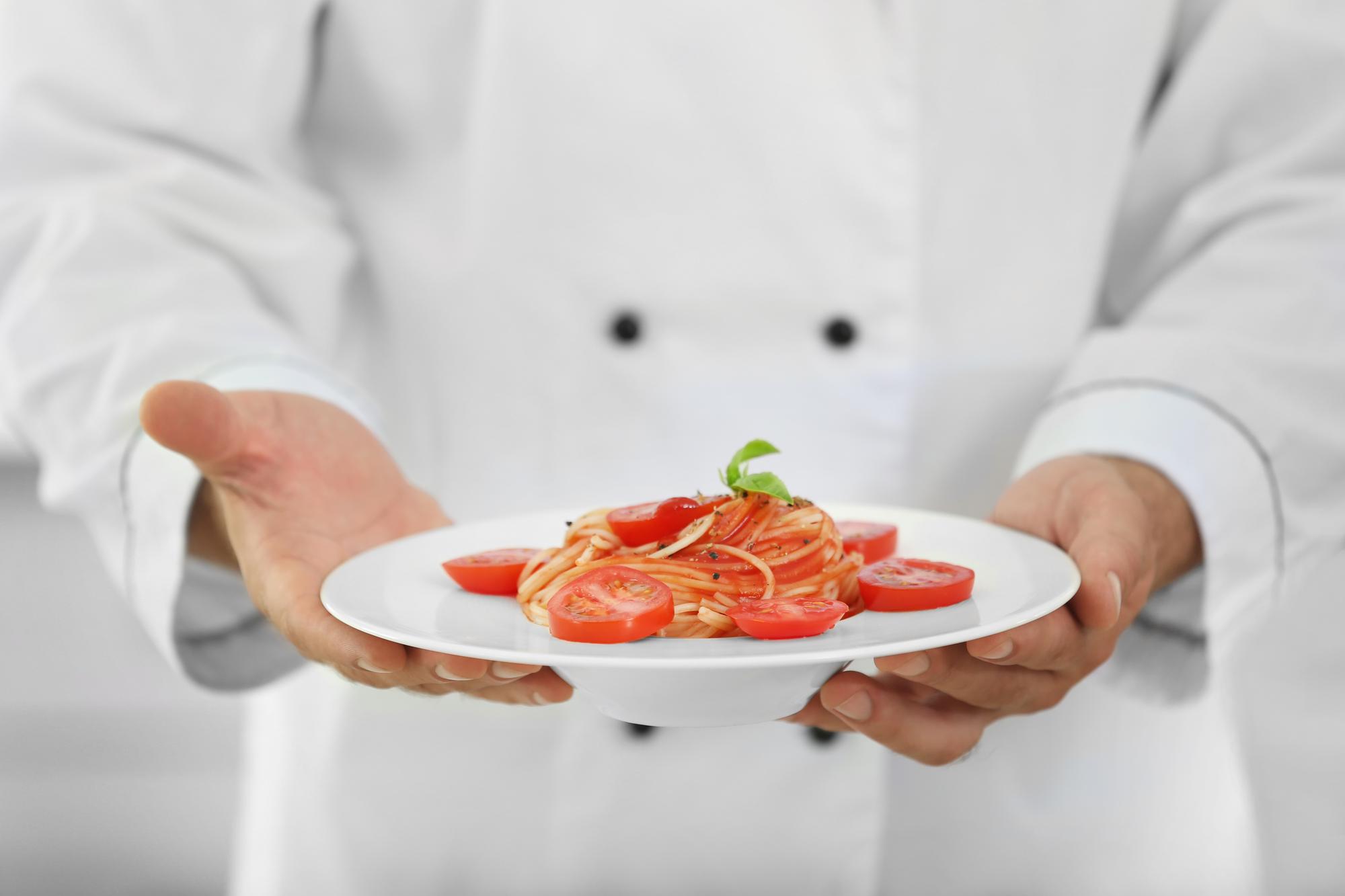 Chef presenting plated gourmet dish on a wooden table